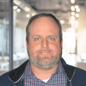 Photo of Mark Robbins standing in a brightly lit office building